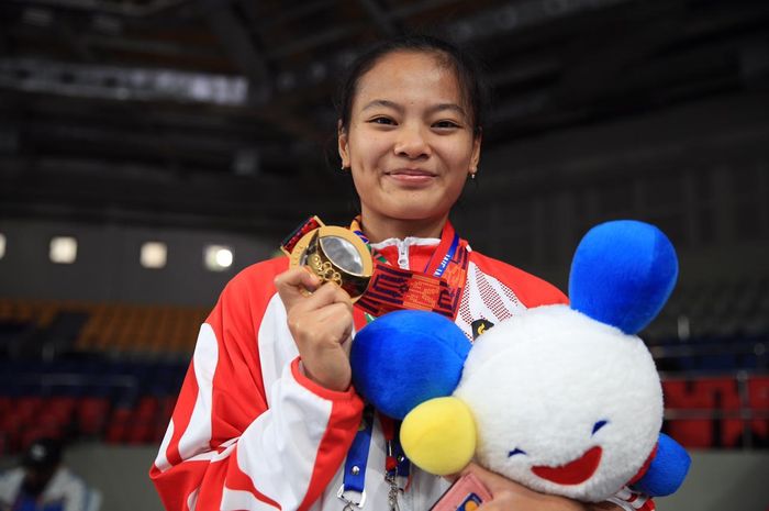Lifter putri Indonesia, Windy Cantika Aisah, berpose dengan medali emas SEA Games kelas 49 kg di Ninoy Aquino Stadium, Manila.