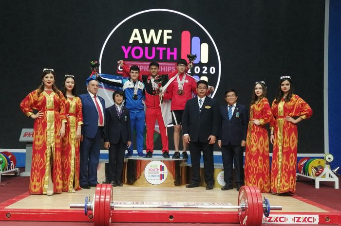 Lifter putra Indonesia, Rizki Juniansyah, berpose setelah meraih medali emas dan memecahkan rekor dunia pada Kejuaraan Angkat Besi Junior Asia 2020 di Sports Complex, Uzbekistan, Minggu (16/2/2020).