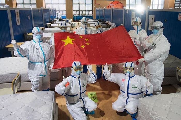 Sejumlah tenaga media di Wuhan, Hubei,   berpose dengan membentangkan bendera China di sebuah tempat perawatan yang sudah tanpa pasien Covid-19.