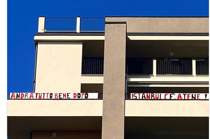 Spanduk berisi pesan semangat untuk melawan COVID-19 di balkon apartemen seorang suporter AC Milan.