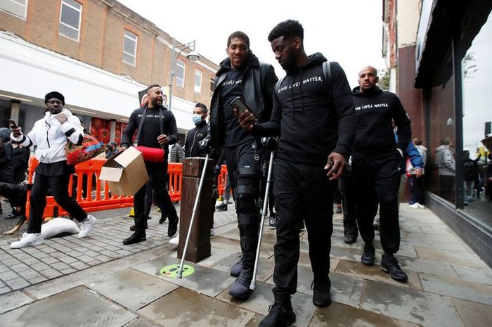 Petinju kelas berat Inggris, Anthony Joshua, terlihat memakai kruk dan penyangga di lutut kirinya saat tengah melakukan aksi protes melawan rasisme dengan tema Black Lives Matter di Watford, Inggris, Sabtu (6/6/2020).