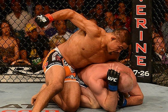 Mantan petarung UFC, Mark Munoz (atas) tengah mengukum lawannya dengan serangan ground and pound.