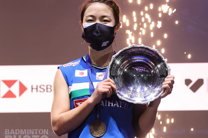 Pebulu tangkis tunggal putri Jepang, Nozomi Okuhara, berpose dengan plakat juara All England Open 2021 di podium kampiun.