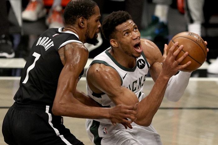 Pebasket Milwaukee Bucks (jersey putih), Giannis Antetokounmpo, berusaha melepas tembakan saat dijaga ketat oleh pemain lawan, Kevin Durant, yang membela tim Brooklyn Nets, pada semifinal Wilayah Timur playoffs NBA 2021.