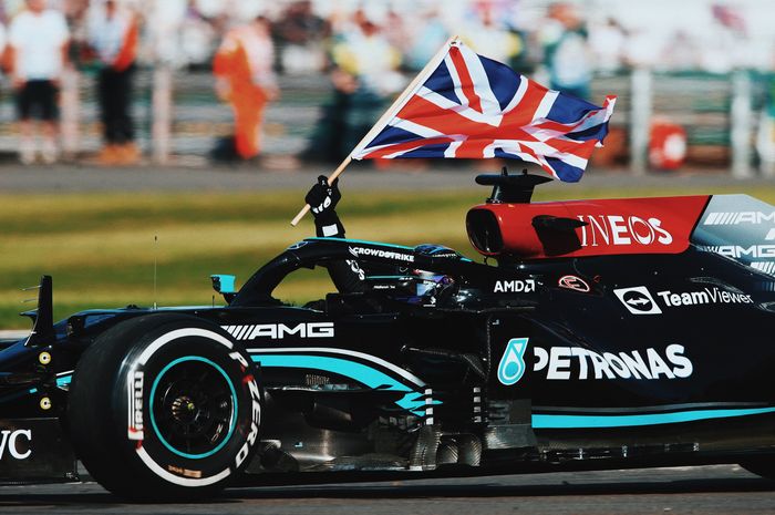 Pembalap Mercedes, Lewis Hamilton, melakukan victory lap usai memenangi balapan Formula 1 (F1) GP Inggris 2021 di Sirkuit Silverstone, Minggu (18/7/2021).