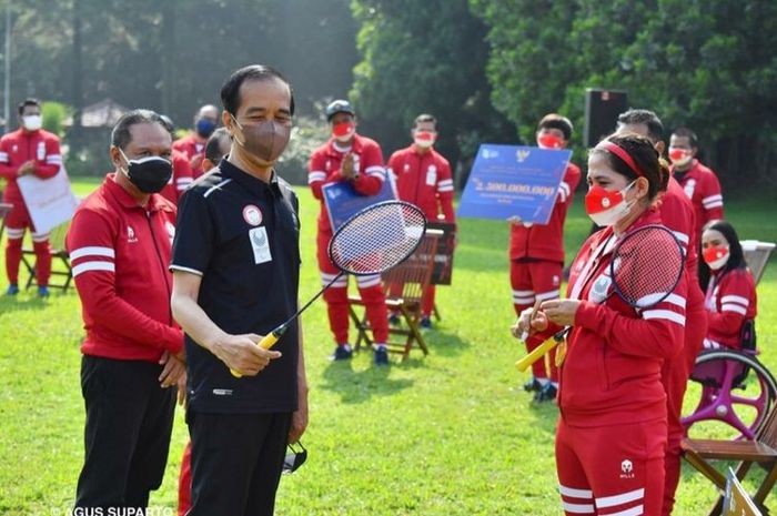Presiden RI, Joko Widodo, memegang raket milik atlet para bulu tangkis, Leani Ratri Oktila, di sela-sela acara penyerahan bonus bagi kontingen Paralimpiade Tokyo 2020 di Istana Kepresidenan Bogor, 17 September 2021.