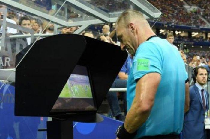 Wasit sedang mengamati kembali rekaman adegan pertandingan melalui video assistant referee (VAR).