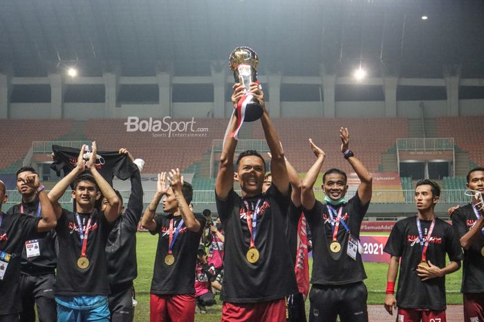 Kapten Persis Solo, Eky Taufik, nampak sedang mengangkat piala dan diikuti oleh rekan-rekannya seusai menjadi kampiun di Liga 2 2021.