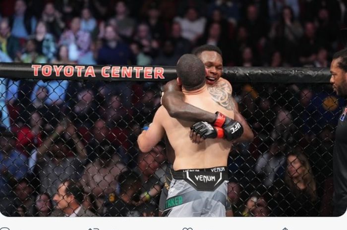 Momen Israel Adesanya dan Robert Whittaker berpelukan usai duel mereka di UFC 271 (13/2/2022).