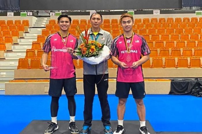 Ganda putra Malaysia, Nur Izzuddin Rumsani (kiri) dan Goh Sze Fei, mengapit pelatih Flandy Limpele dari Indonesia usai juara German Open 2022.