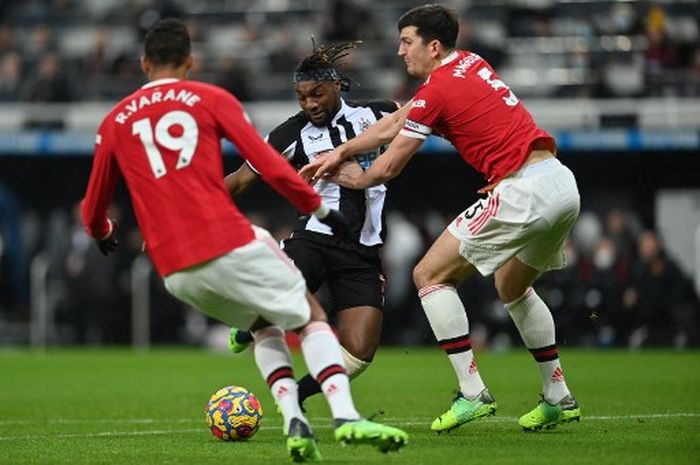 Harry Maguire (kanan) dan Raphael Varane mengawal ketat Allan Saint-Maximin dalam duel Liga Inggris Newcastle United vs Manchester United di St James' Park (27/12/2021).