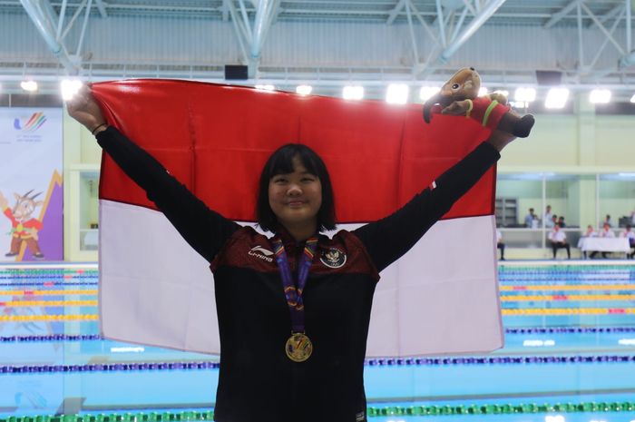 Perenang Indonesia, Flairene Candrea Wonomiharjo, mengangkat bendera Merah Putih setelah meraih medali emas SEA Games 2021 dari nomor 100 meter gaya punggung putri di My Dinh Aquatics Cente, Hanoi, Vietnam, 17 Mei 2022.