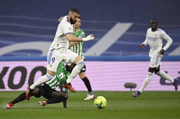 Striker Real Madrid, Karim Benzema, berusaha menghindari tekel dari bek Real Betis, Youssouf Sabaly, dalam laga Liga Spanyol di Stadion Santiago Bernabeu, Jumat (20/5/2022).