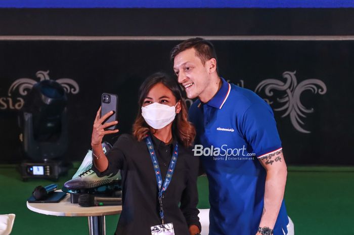 Pemain Fenerbahce, Mesut Ozil (kanan), nampak menyambut seorang fan yang ingin melakukan foto selfie di Kantor Kementerian Pariwisata dan Ekonomi Kreatif Republik Indonesia, Jakarta, 25 Mei 2022.