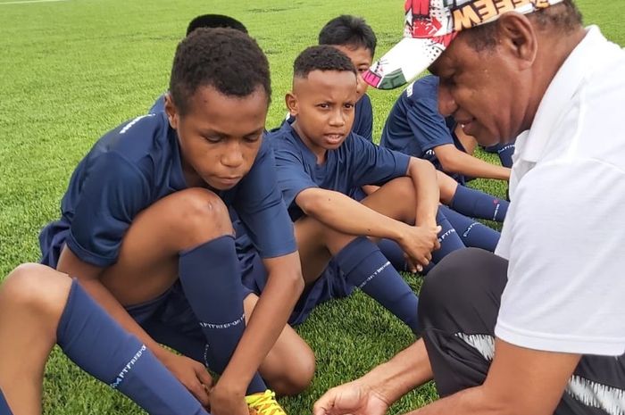 Legenda sepak bola Indonesia, Rully Nere, mengajarkan cara memakai sepatu yang benar kepada para peserta Papua Football Academy di Merauke, Sabtu-Minggu (18-19/6/2022).