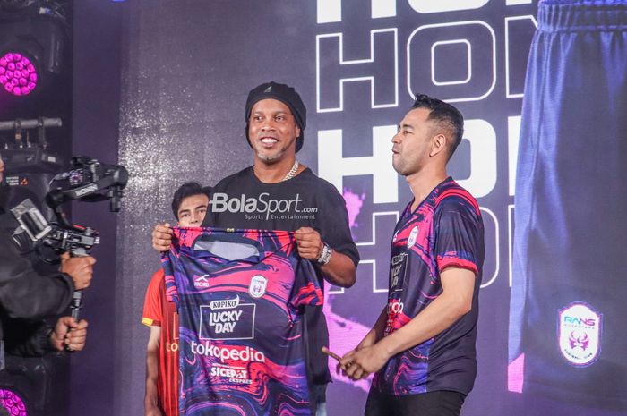Ronaldinho (kiri) sedang memegangi jersey baru RANS Nusantara FC ditemani oleh Raffi Ahmad (kanan) selaku chairman tim di Menara Mandiri, Senayan, Jakarta, 24 Juni 2022.