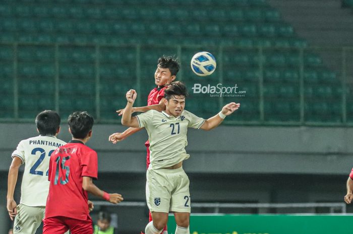 Pemain timnas U-19 Laos, Vongsakda Chanthaleuxay (belakang), sedang berduel udara merebut bola dengan pilar timnas U-19 Thailand bernama Nattakit Busting (depan) saat bertanding di Stadion Patriot Candrabhaga, Bekasi, Jawa Barat, 13 Juli 2022.