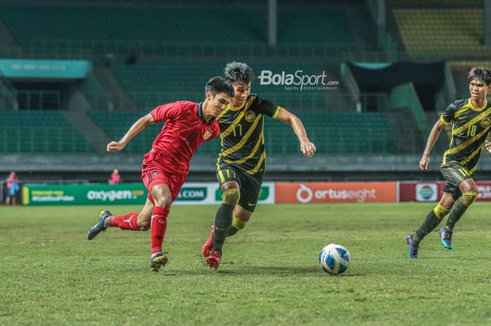 Pemain timnas U-19 Laos, Phoutthavong Sangvilay (kiri), sedang berusaha melewati pilar timnas U-19 Malaysia bernama Fakrul Fareez zaldi (kanan) di Stadion Patriot Candrabhaga, Bekasi, Jawa Barat, 15 Juli 2022.