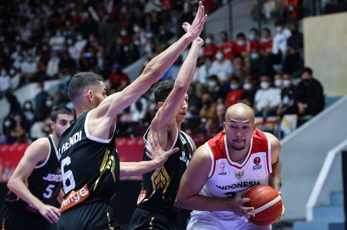 Pemain timnas basket Indonesia, Arki Dikania Wisnu (jersey putih), mempertahankan bola di tengah adangan pemain Yordania pada pertandingan Grup A FIBA Asia Cup 2022 di Istora Gelora Bung Karno, Senayan, Jakarta, 14 Juli 2022.