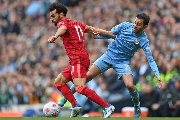 Mohamed Salah (kiri) berduel dengan Bernardo Silva dalam partai Liga Inggris antara Manchester City vs Liverpool di Etihad Stadium, Manchester (10/4/2022).
