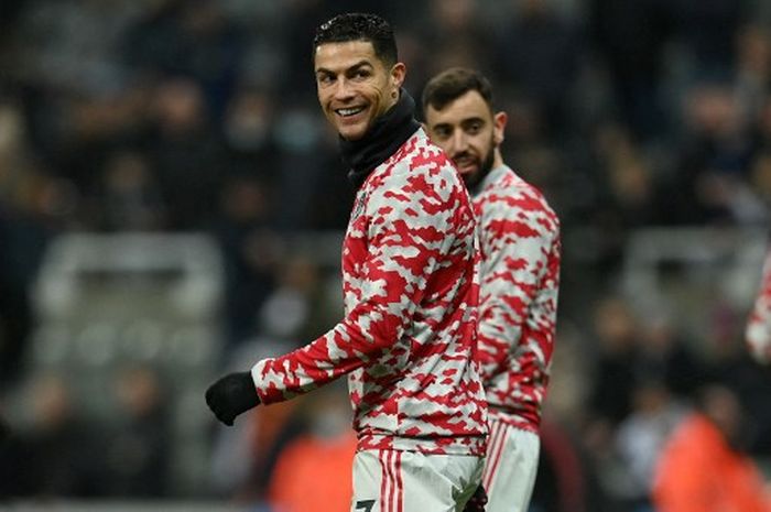 Cristiano Ronaldo tersenyum bersama Bruno Fernandes dalam pemanasan jelang duel Liga Inggris, Newcastle United vs Manchester United, di Stadion St. James' Park, 27 Desember 2021.