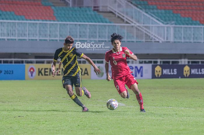 Pemain timnas U-17 Indonesia, Muhammad Kafiatur Rizky (kanan), sedang menggiring bola dan dibayangi bek timnas U-17 Malaysia bernama Muhammad Faris Danish (kiri) dalam laga Kualifikasi Piala Asia U-17 2023 di Stadion Pakansari, Bogor, Jawa Barat, 9 Oktober 2022.