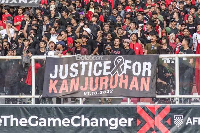 Suporter timnas Indonesia membentangkan spanduk terkait tragedi Kanjuruhan dalam laga pekan pertama Grup A Piala AFF 2022 di Stadion Gelora Bung Karno, Senayan, Jakarta, 23 Desember 2022.