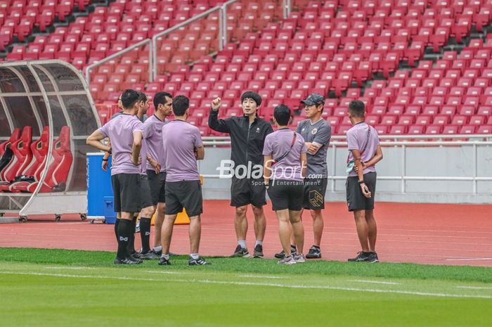 Pelatih timnas Indonesia, Shin Tae-yong (topi) serta salah satu asistennya yang berjaket hitam sedang berkomunikasi dengan wasit saat berlatih di Stadion Gelora Bung Karno, Senayan, Jakarta, 28 Desember 2022.