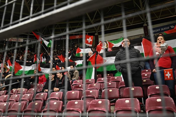 Fan timnas Swiss mengibarkan bendera Palestina saat menghadapi timnas Israel di Kualifikasi Euro 2024 (28/3/2023), sementara Indonesia gagal jadi tuan rumah Piala Dunia U-20 2023 karena protes tolak negara yang sama.