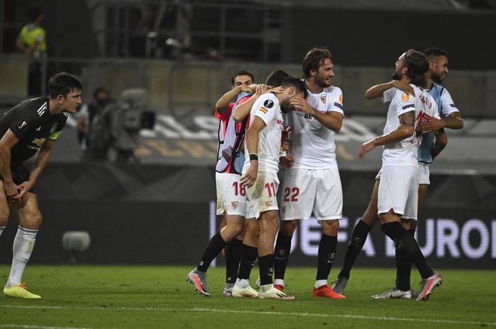 Para pemain Sevilla (kanan) merayakan gol sementara bek Manchester United, Harry Maguire, lesu dalam laga semifinal Liga Europa (16/8/2020). Kedua tim bertemu lagi di perempat final Liga Europa 2022-2023.