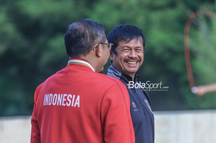 Pelatih timnas U-22 Indonesia, Indra Sjafri (kanan), memberikan senyuman saat memantau para pemainnya saat berlatih di Hotel Sultan, Senayan, Jakarta, Jumat (21/4/2023) sore.