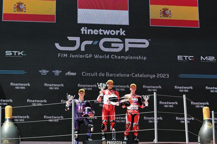Pembalap Indonesia, Fadillah Arbi Aditama (tengah), merayakan kemenangannya dalam balapan kedua FIM JuniorGP seri Catalunya di Sirkuit Catalunya, Spanyol, 16 Juli 2023.