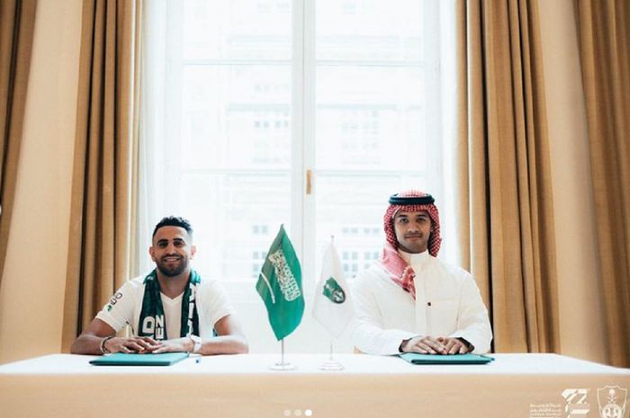 Riyad Mahrez berfoto dengan perwakilan Al-Ahli seusai menandatangani kontrak untuk bermain di Liga Arab Saudi.