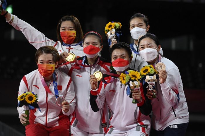 Greysia Polii/Apriyani Rahayu (tengah) memamerkan medali emas mereka di podium usai final bulu tangkis ganda putri Olimpiade Tokyo 2020 di Musashino Forest Sports Plaza, Tokyo, Jepang, 2 Agustus 2021. Tampak juga dalam foto Chen Qing Chen/Jia Yi Fan dari China (kiri) yang merebut perak dan Kim So-ye