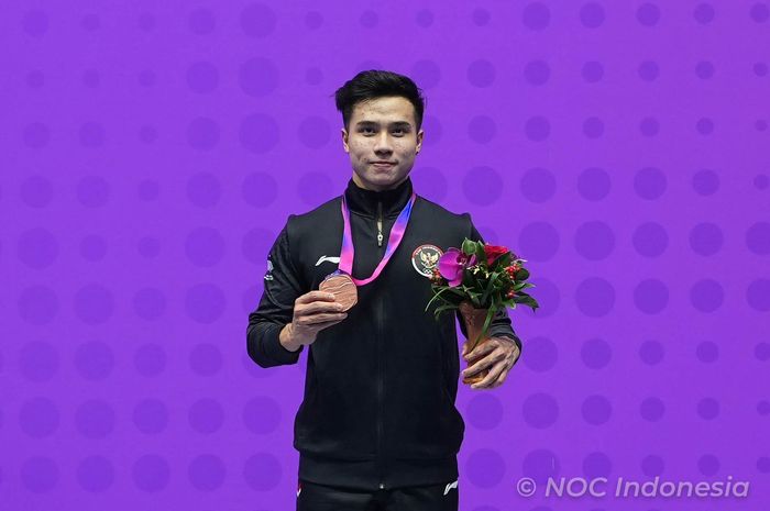 Pewushu putra Indonesia, Seraf Naro Siregar, berpose dengan medali perunggu nomor gunshu putra, Rabu (27/9/2023).
