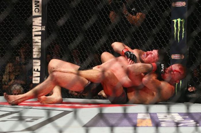 Georges St-Pierre mengalahkan Michael Bisping untuk menjadi juara kelas menengah UFC dalam laga terakhirnya pada 4 November 2017 di Madison Square Garden, New York. NEW YORK, NY - NOVEMBER 04: Michael Bisping of England is pinned by Georges St-Pierre of Canada in their UFC middleweight championship bout during the UFC 217 event at Madison Square Garden on November 4, 2017 in New York City.   Mike Stobe/Getty Images/AFP (Photo by Mike Stobe / GETTY IMAGES NORTH AMERICA / Getty Images via AFP)