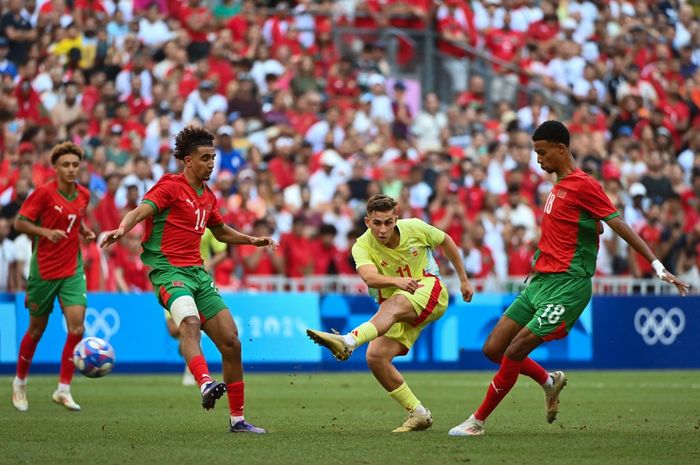 Pemain timnas Spanyol, Fermin Lopez (tengah) melepaskan tembakan di antara para pemain timnas Maroko pada semifinal Olimpiade 2024 di Stade de Marseille (5/8/2024).