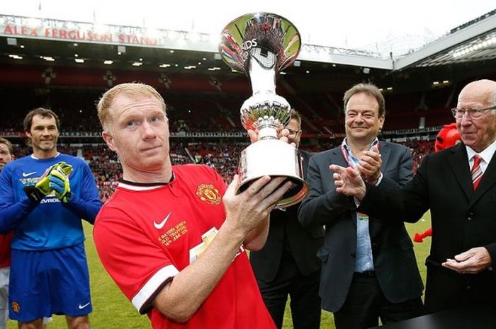   Mantan gelandang Manchester United, Paul Scholes, memegang trofi yang diserahkan oleh pemain legendaris Manchester United, Bobby Charlton, usai laga amal antara Legenda Manchester United melawan bayern Muenchen All Stars di Stadion Old Trafford, Manchester, 14 Juni 2015.  