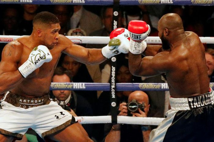 Petinju kelas berat Inggris, Anthony Joshua (kir), dan Carlos Takam (Prancis), saling melayangkan pukulan pada duel perebutan gelar juara dunia di Principality Stadium, Cardiff, Wales, Sabtu (28/10/2017). Joshua dinyatakan menang TKO atas Takam pada ronde ke-10.