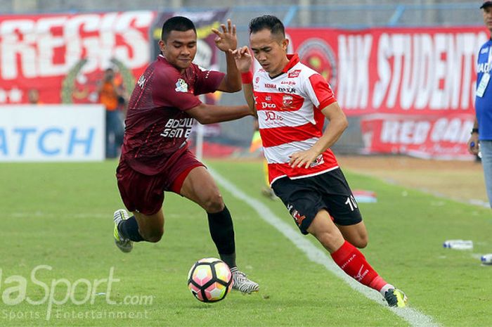 Gelandang Madura United, Slamet Nurcahyo (kanan), berebut bola dengan gelandang PSM Makassar, Asnawi Mangkualam Bahar, dalam laga pekan ke-17 Liga 1 di Stadion Gelora Bangkalan, Jawa Timur, Sabtu (29/7/2017) sore.