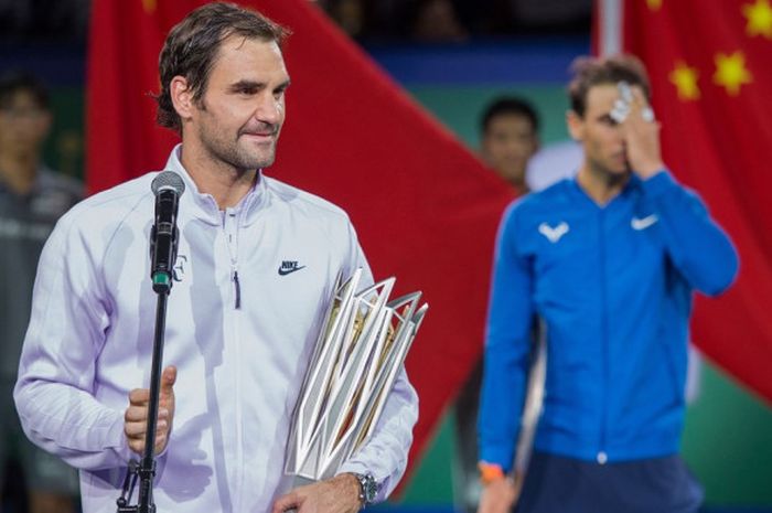 Petenis tunggal putra Swiss, Roger Federer, mengucapkan kata sambutan seusai menjuarai turnamen Shanghai Masters. Federer menjadi kampiun setelah menundukkan petenis Spanyol, Rafael Nadal (belakang),  6-4, 6-3, Minggu (15/10/2017).