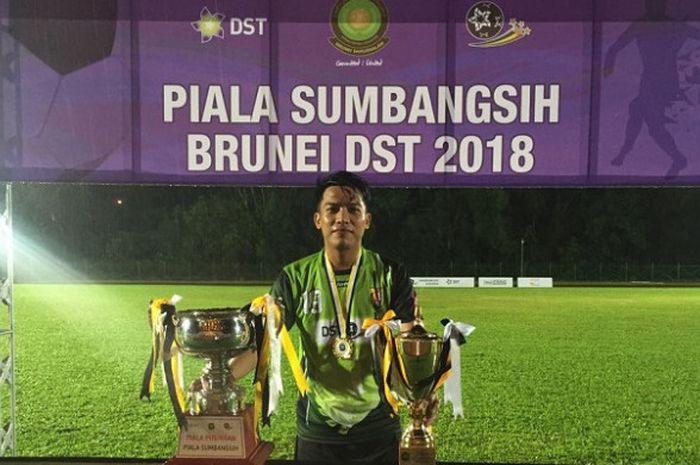 Gelandang klub Brunei, Indera SC asal Indonesia, Iner Sontany Putra memamerkan trofi Piala Sumbangsi