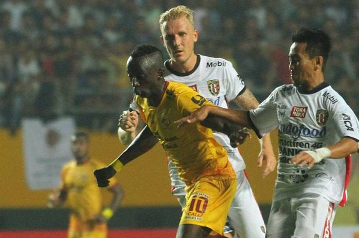 Pemain Bali United, Nick van der Velden dan Taufik berusaha menghentikan pergerakan pemain Sriwijaya FC, Makan Konate pada babak semifinal leg pertama di Stadion Gelora Sriwijaya Jakabaring, Palembang