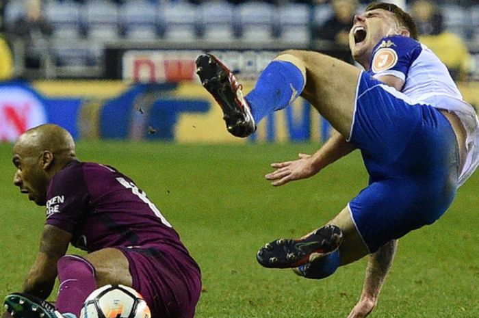 Bek kiri Manchester City, Fabian Delph, melepaskan tekel kepada gelandang Wigan Athletic, Max Power, dalam laga babak kelima Piala FA di Stadion DW, Wigan, Inggris, pada 19 Februari 2018.