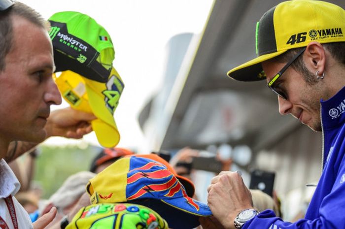 Pebalap MotoGP yang membela tim Movistar Yamaha, Valentino Rossi, menandatangani pernak-pernik yang dibawa para fan di sela GP Austria di Red Bull Ring, Spielberg, Jumat (11/8/2017).