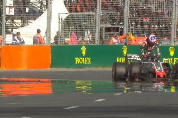 Pebalap Haas, Romain Grosjean, keluar dari mobilnya karena mengalami masalah pada ban pada GP Australia di Sirkuit Melbourne, Australia, Minggu (25/3/2018).