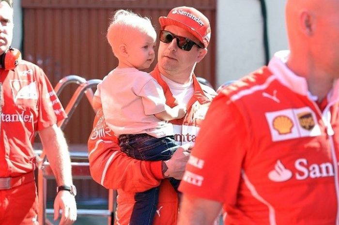 Pebalap Ferrari, Kimi Raikkonen, sedang menggendong anaknya, Robin, di Circuit de Barcelona-Catalunya, 10 Maret 2017.
