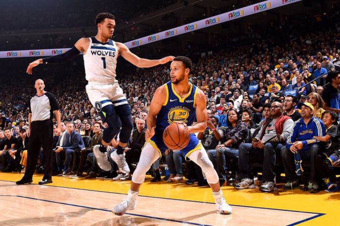 Pemain Golden State Warriors, Stephen Curry (jersey biru #30), saat melakukan fake shot terhadap pemain Minessota Timberwolves, Tyus Jones (jersey putih #1), pada laga NBA 2018/19 yang digelar Jumat (2/11/2018) malam waktu Amerika Serikat.