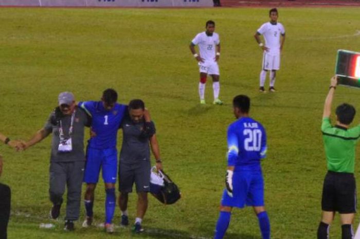 Kiper timnas U-22 Indonesia, Satria Tama dipapah keluar lapangan saat laga kontra Vietnam pada partai keempat Grup B SEA Games 2017 di Stadion MP Selayang, Selangor, 22 Agustus 2017. 