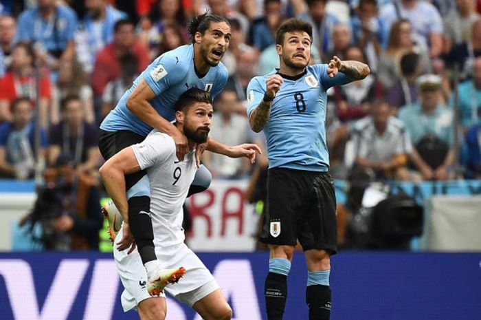 Dua pemain Uruguay, Nahitan Nandez (kanan) dan Martin Caceres, berebut bola dengan penyerang Prancis, Olivier Giroud, dalam pertandingan babak perempat final Piala Dunia 2018, 6 Juli 2018 di Nizhny Novgorod.